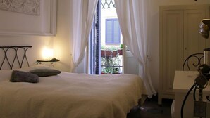A bedroom with a bed, a bedside table, a lamp, a window with curtains, and a view of the outside. - La Casa di Amy (Rome)