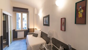 A hotel room with a bed, a desk, a radiator, and a window. - La Casa di Amy (Rome)