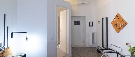Une chambre d’hôtel moderne équipée d’un lit, d’une table de chevet, d’une lampe et donnant sur le couloir.