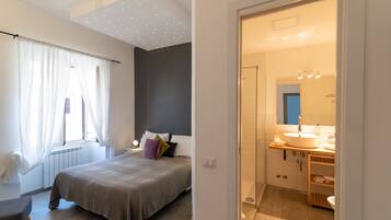 A bedroom with a bed, bedside table, and a window with curtains.