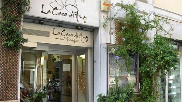 The storefront of 'La Caca d'Itinera' with a glass entrance and greenery around. - La Casa di Amy (Rome)