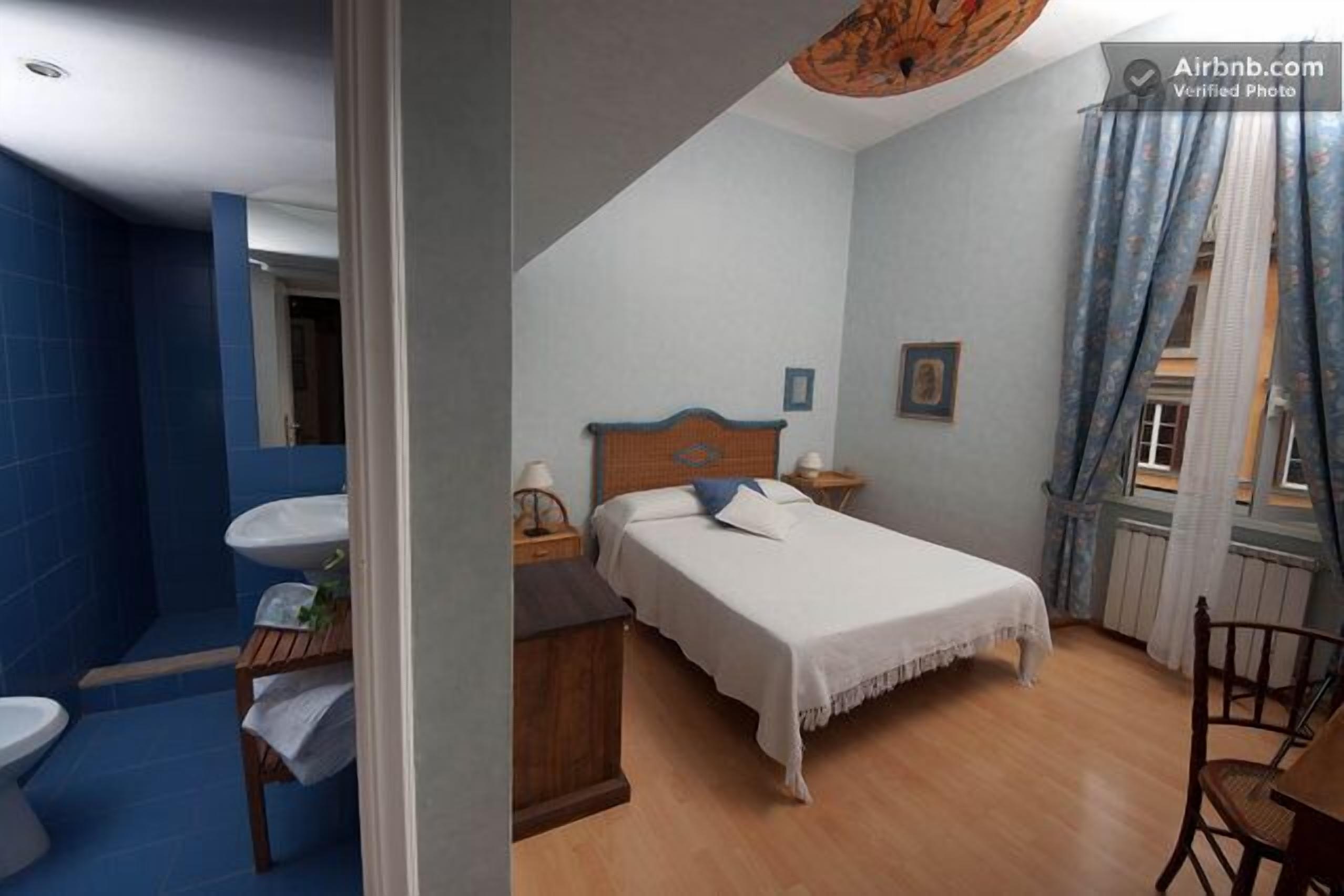 A bedroom with a bed, bedside table, and a window with curtains.
