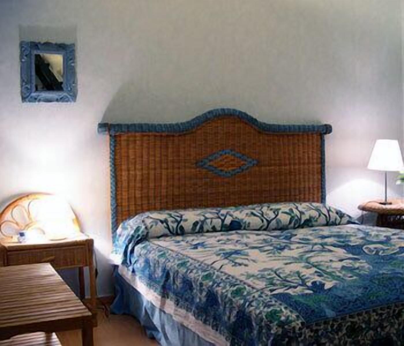 Un dormitorio con cama, mesita de noche, lámpara y una pequeña mesa.