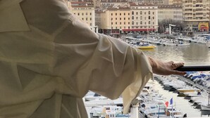 Una persona contemplando un puerto deportivo con barcos y edificios al fondo.
