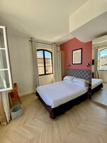 Una habitación de hotel con una cama grande, una ventana con cortinas, una silla y una mesita.