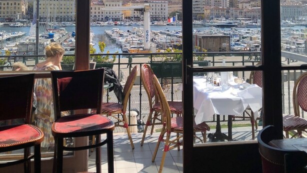 Una terraza con vista a un puerto deportivo y un edificio en la cima de una colina.