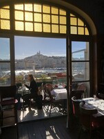 A restaurant with a view of a cityscape, including a hilltop building and a marina.