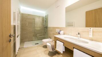 A modern bathroom with a glass-enclosed shower, a double sink vanity, and a toilet.