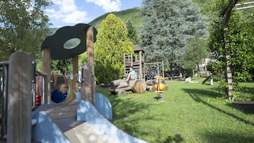 A playground with a slide, climbing structures, and a wooden playhouse.