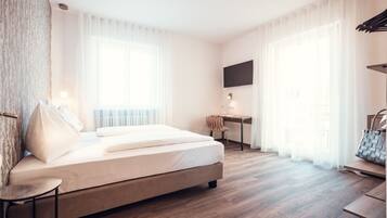 A modern hotel room with a large bed, a desk, and a TV mounted on the wall.