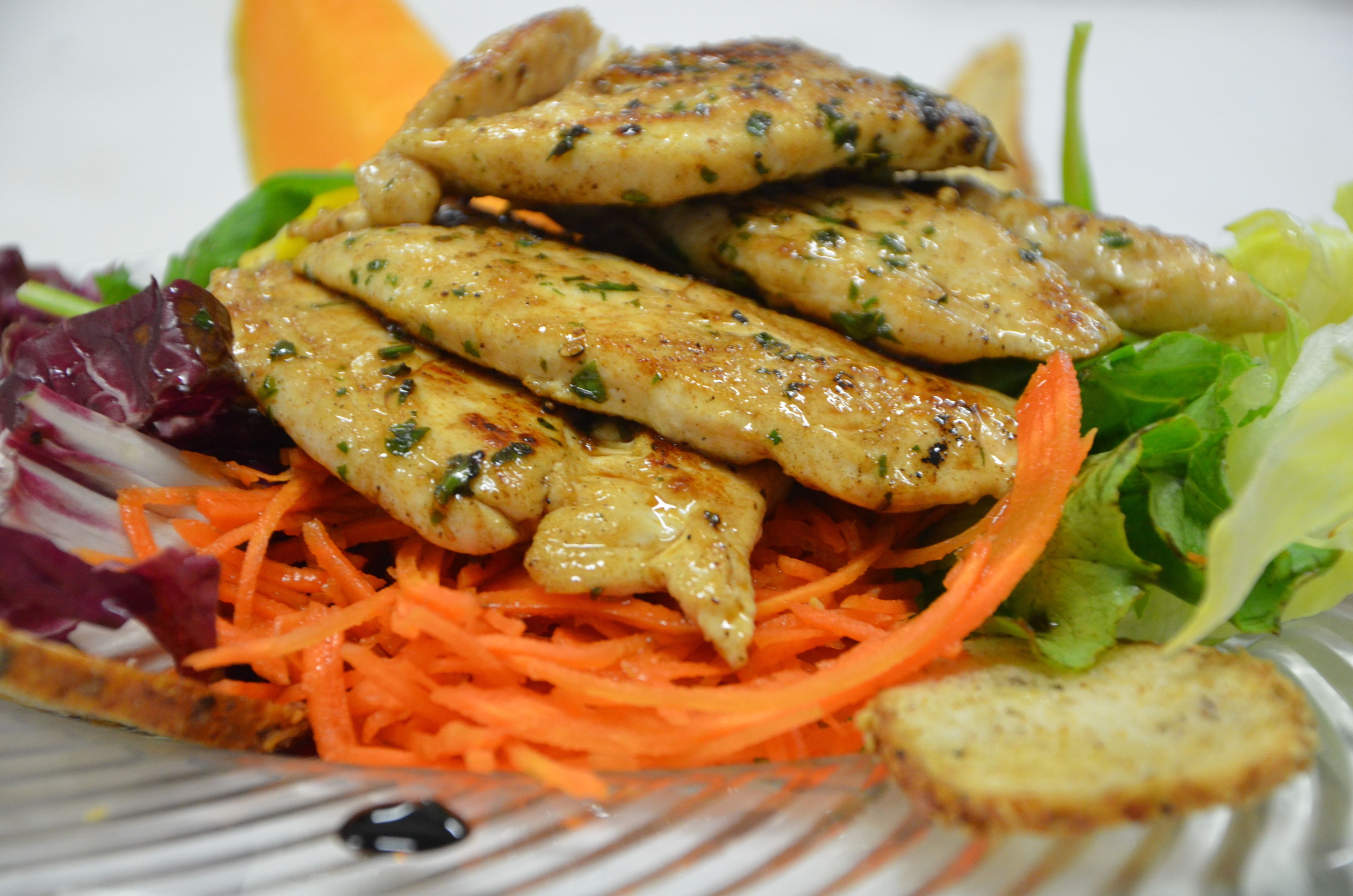A plate of grilled chicken with vegetables and a side of bread.