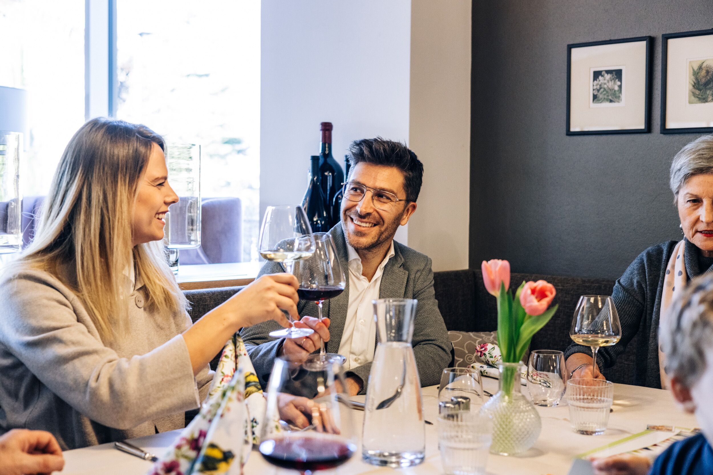 A dining table with wine glasses, a bottle of wine, and a vase with flowers.
