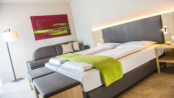 A modern hotel room with a large bed, bedside tables, a desk, and a floor lamp.