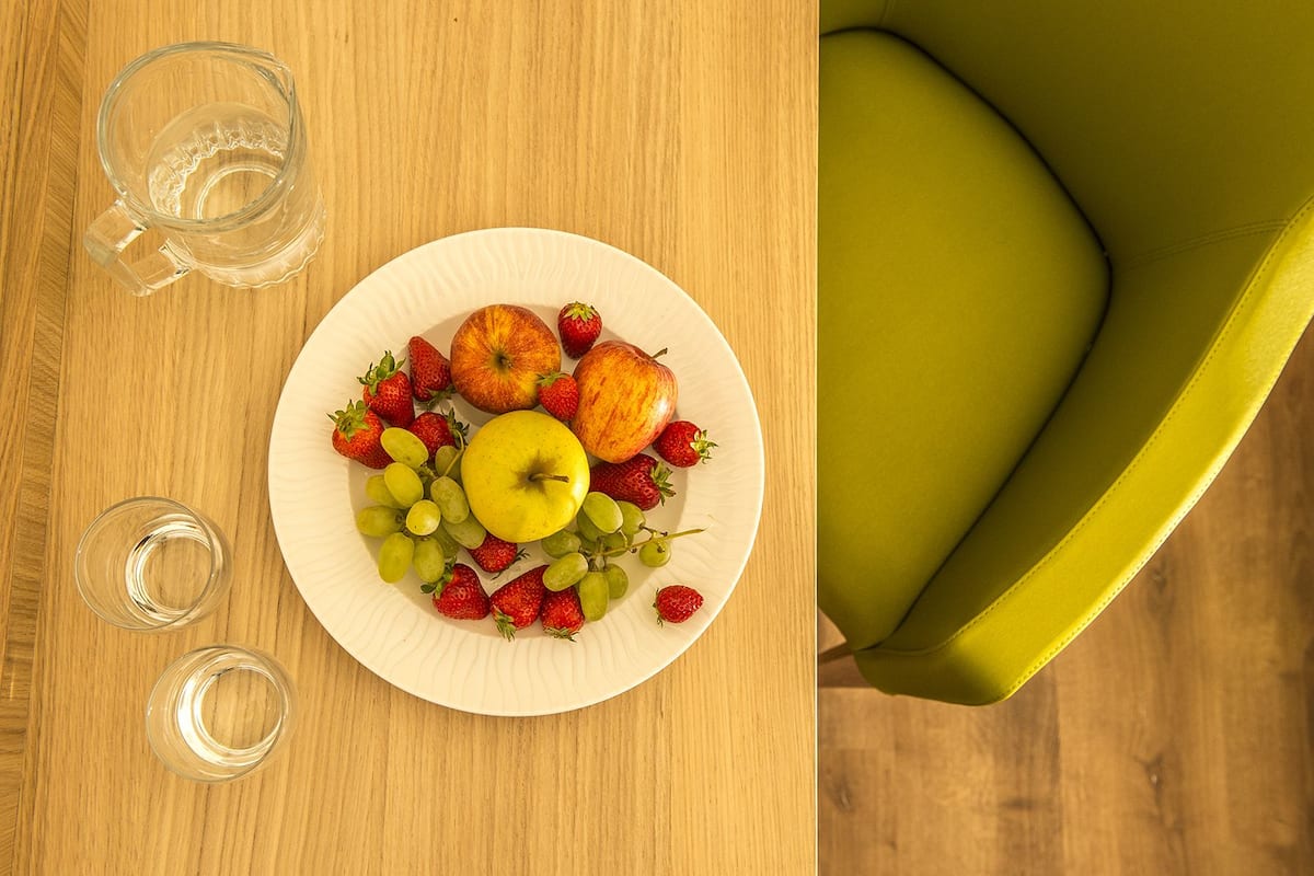 A wooden table with a plate of fruit and two glasses.