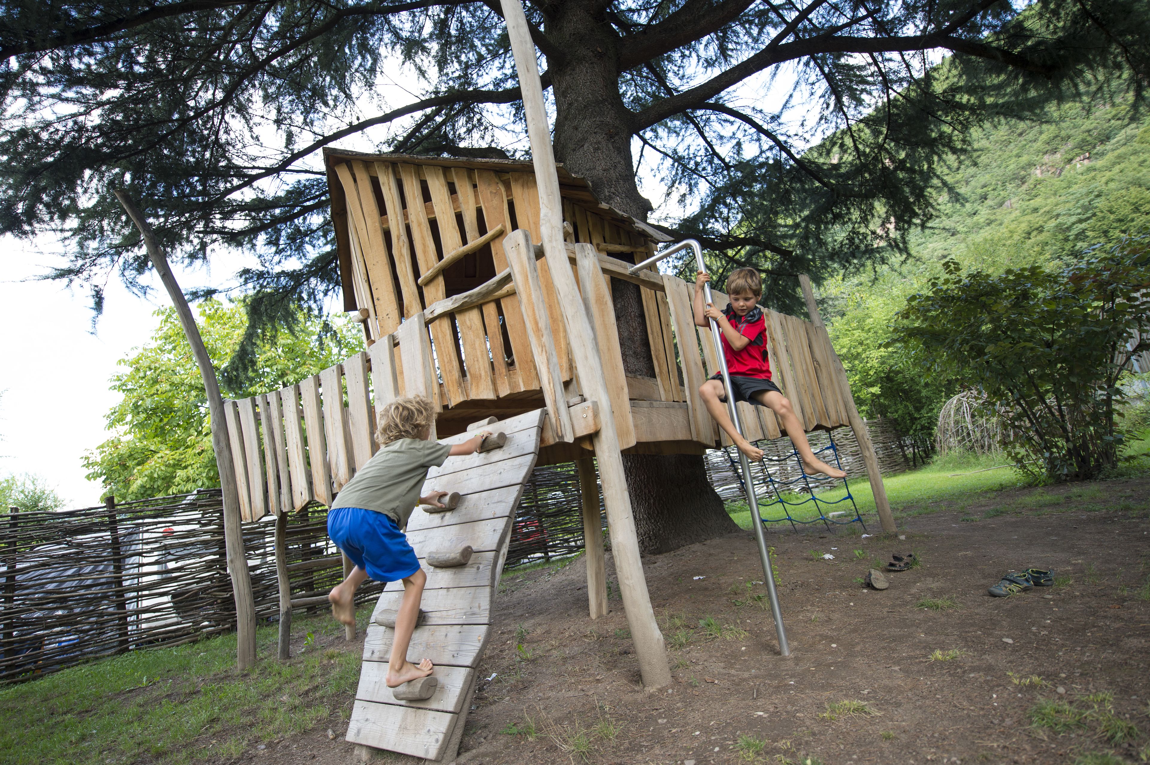 A wooden play structure with climbing elements and a rope ladder.