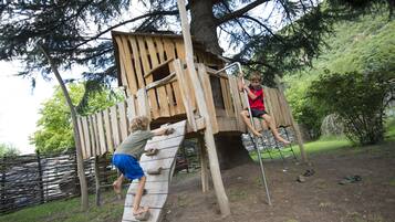 Una estructura de juego de madera con elementos para escalar y una escalera de cuerda.