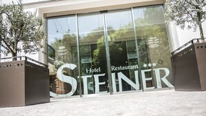 Een hotelingang, met de naam 'STEINER' duidelijk zichtbaar op de glazen deuren.