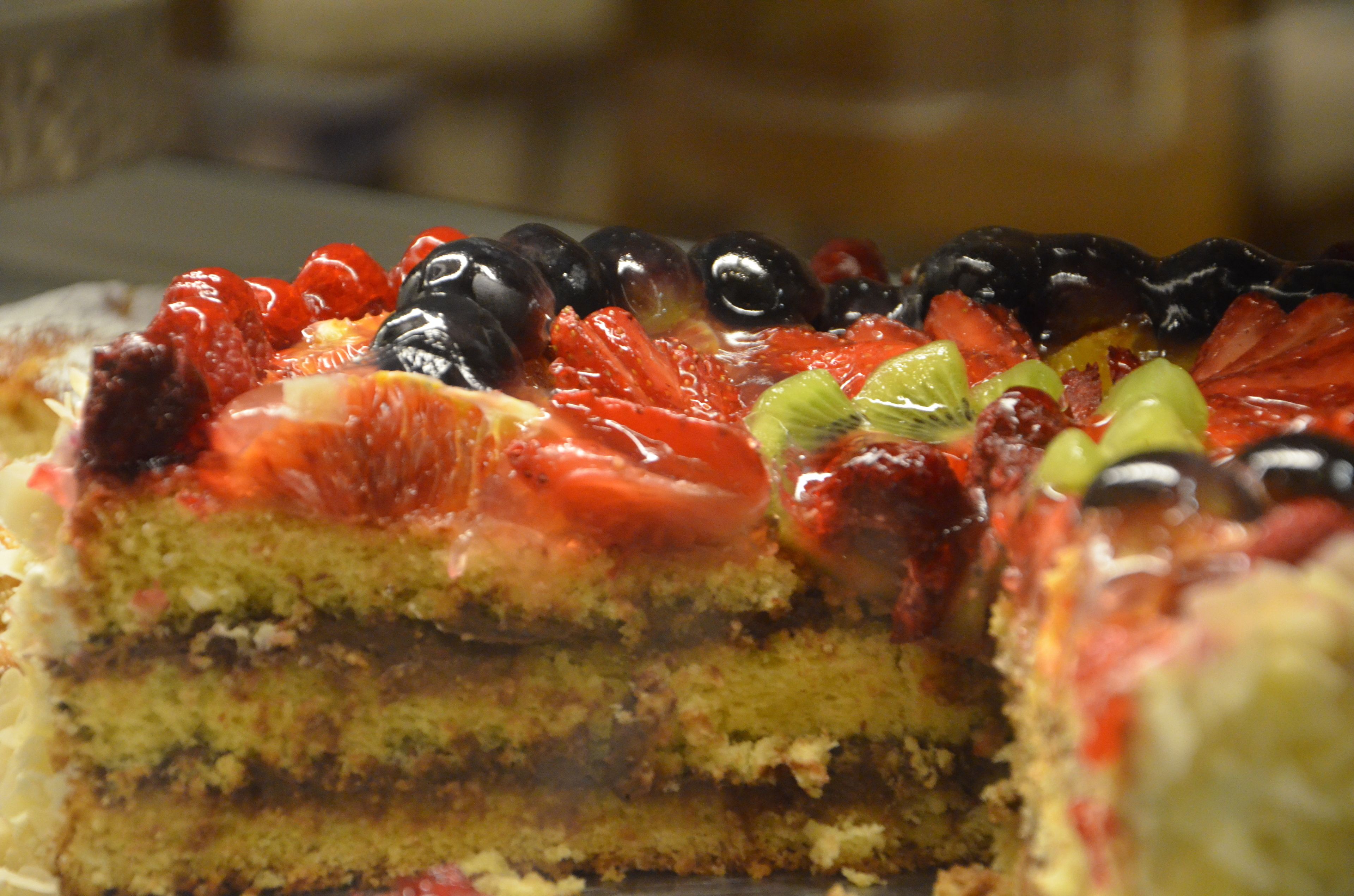 A slice of layered cake topped with various fruits.