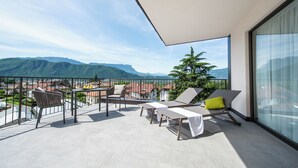 Een balkon met uitzicht op bergen, een tafel en stoelen.