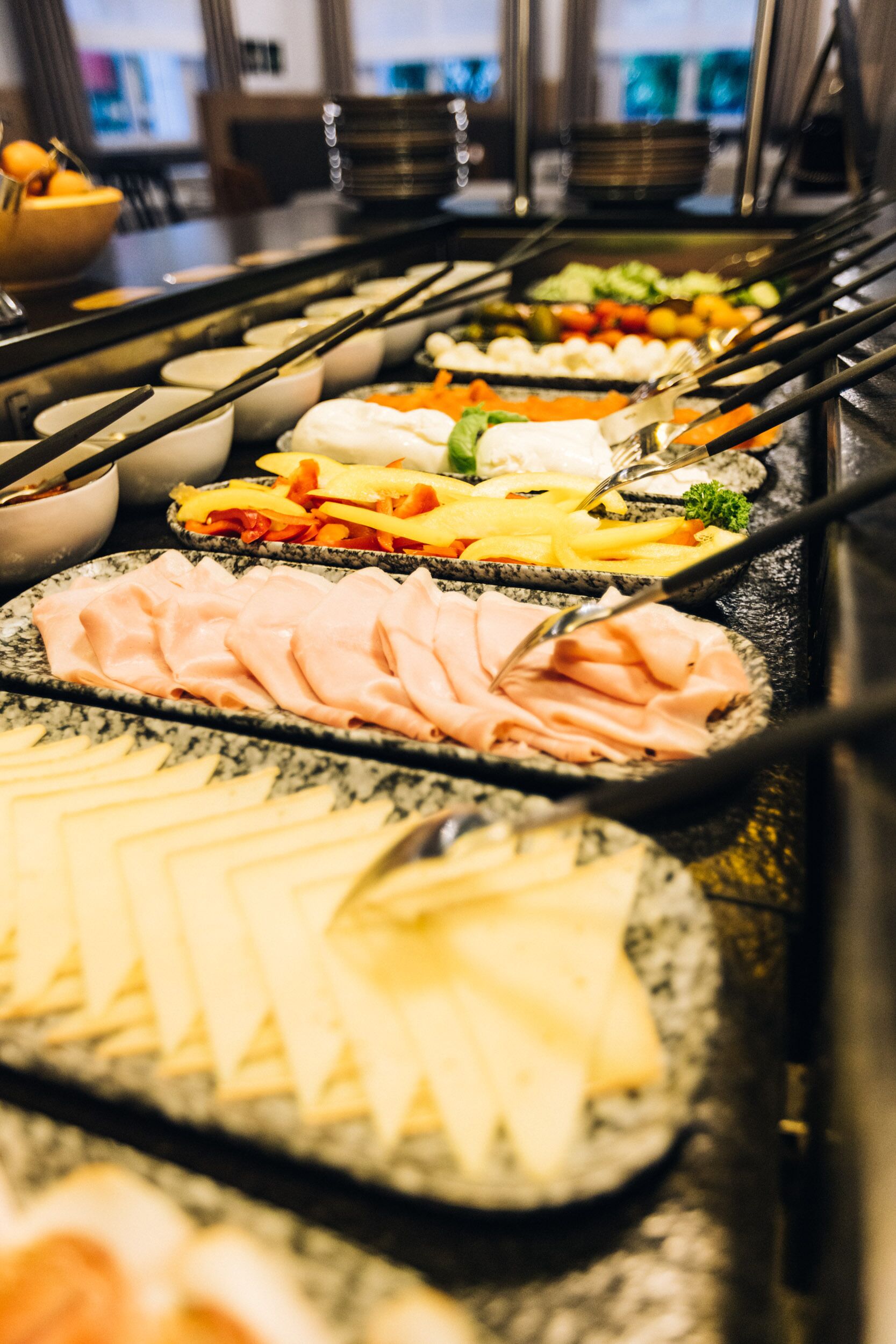A buffet with various food items including meats, cheeses, and vegetables.