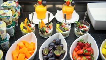En morgenmadsbuffet med forskelligt frugt, yoghurt og appelsinjuice.