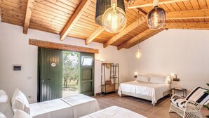 A room with two beds, a wicker chair, and a hanging light fixture.
