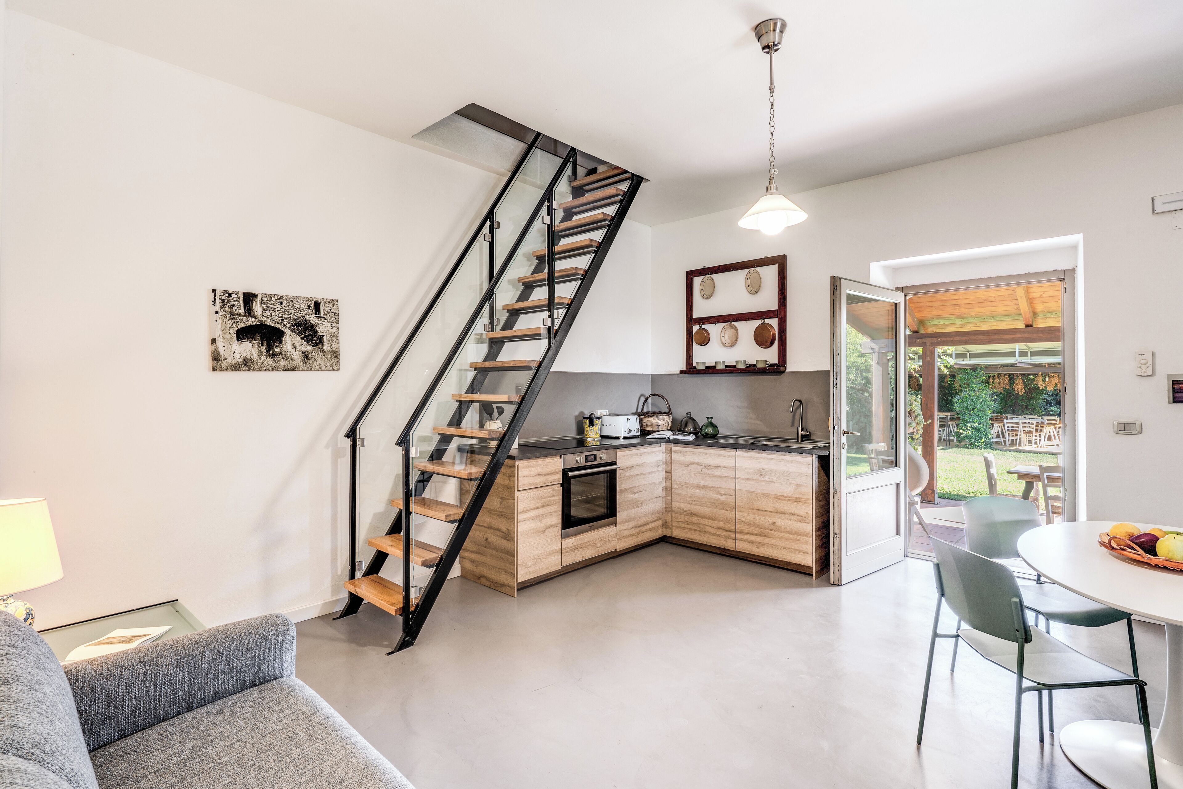 Eine moderne Küche mit einer Holztreppe, einem Essbereich mit Tisch und Stühlen und Blick ins Freie.