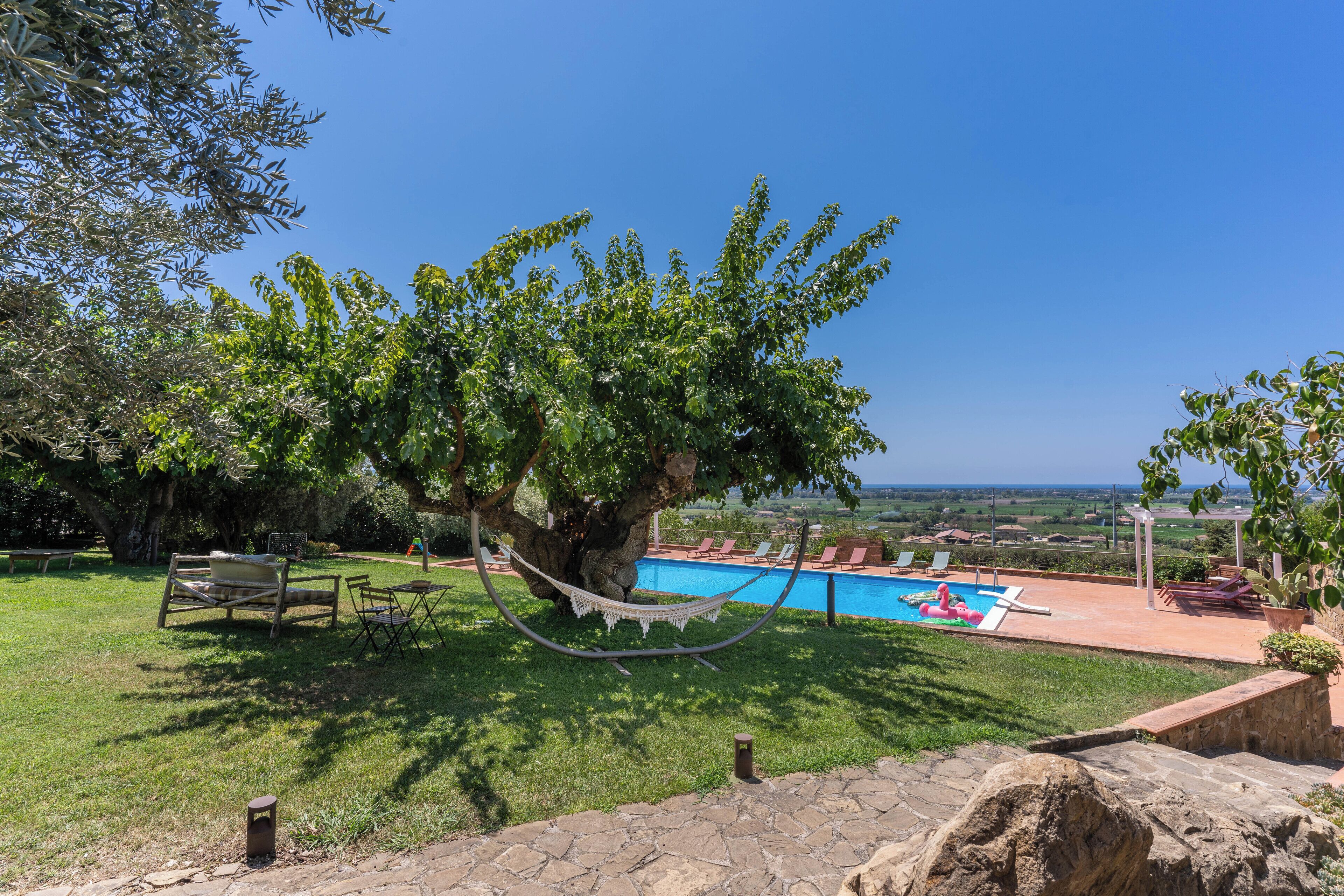 Ein Poolbereich mit Hängematte, Liegestühlen und Blick auf die Landschaft.