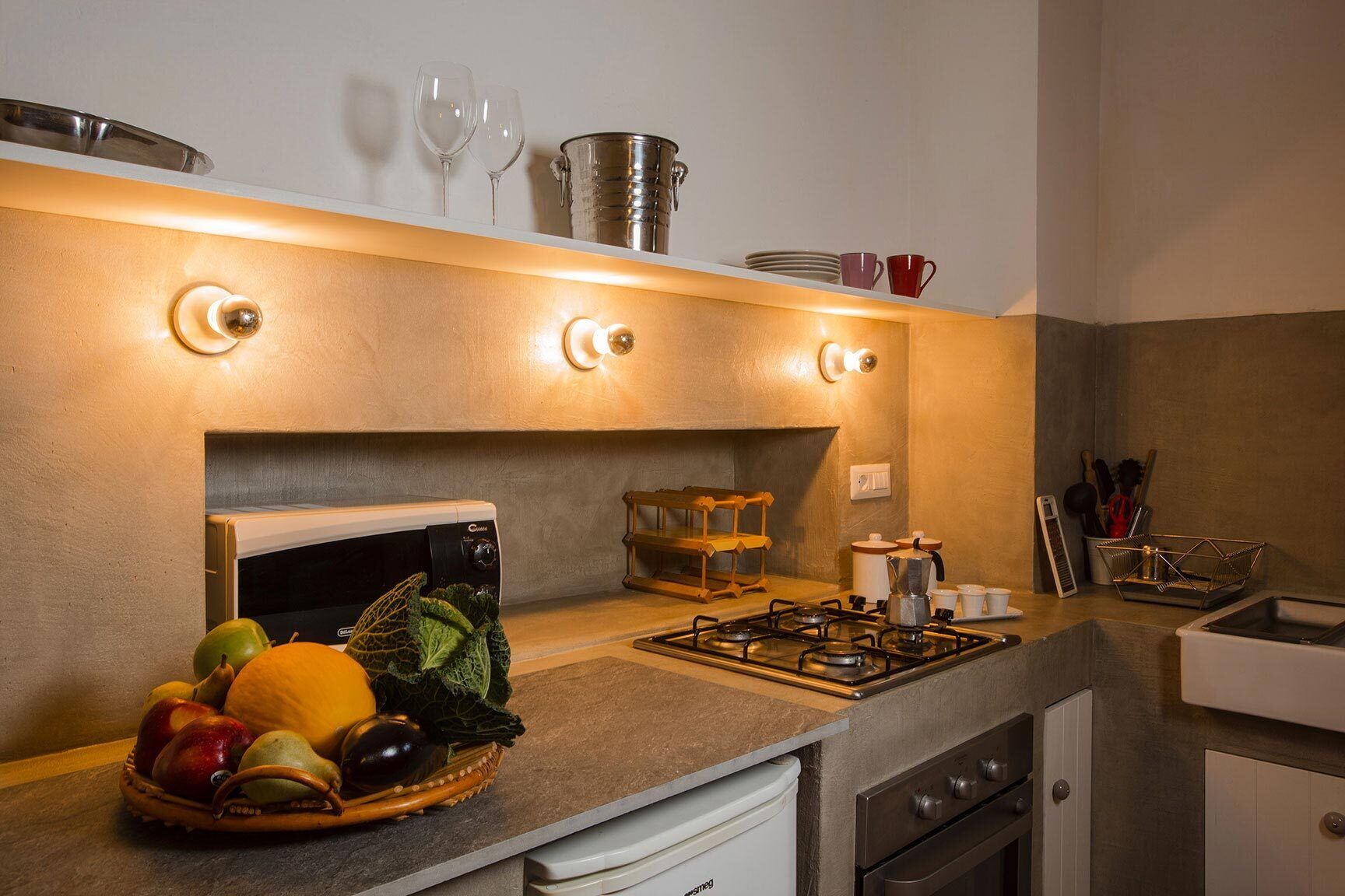 A kitchen with a gas stove, a microwave, and a fruit bowl on the counter.