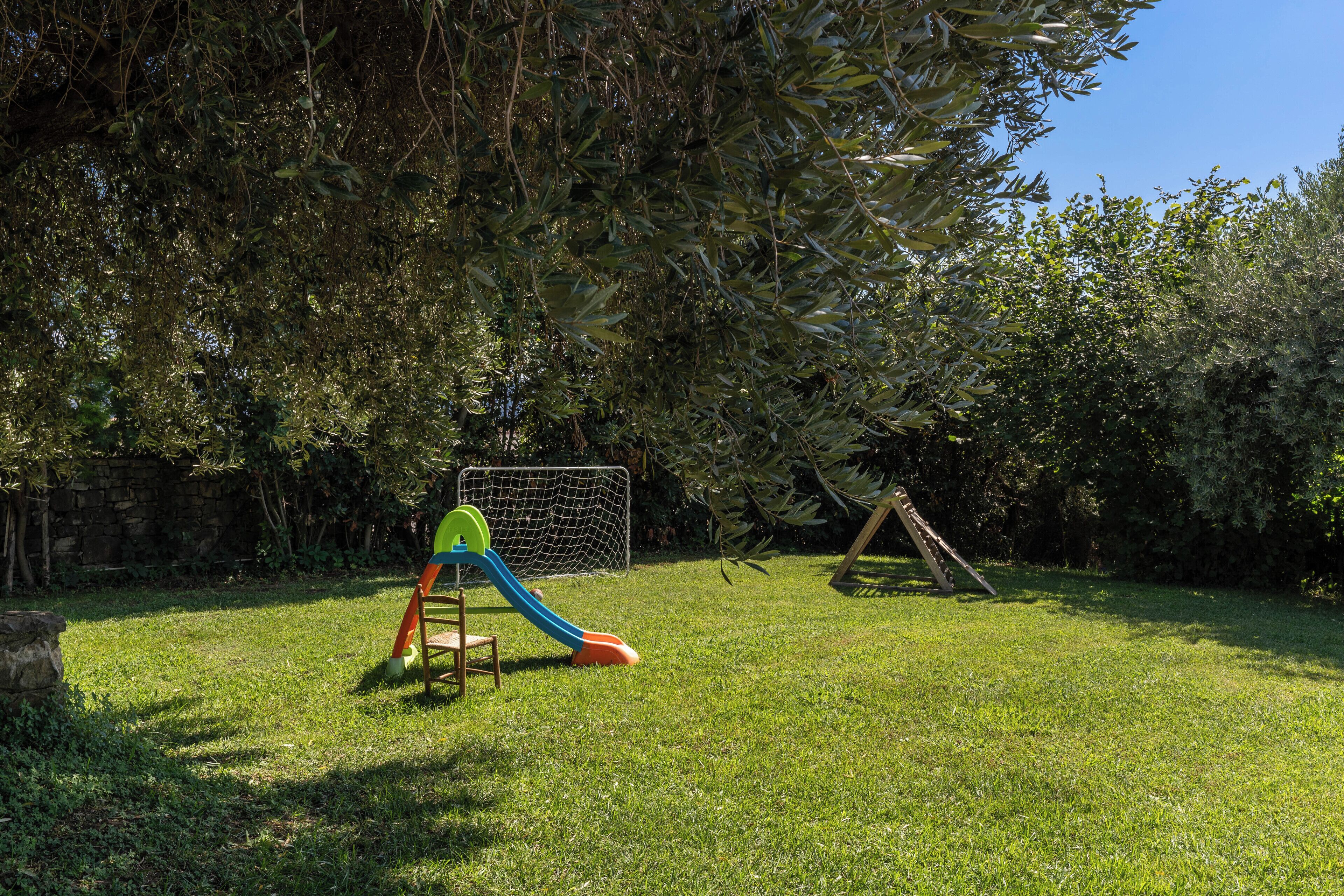 A grassy outdoor area with a slide and a swing set.