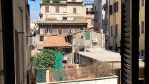 A narrow street with buildings on both sides, featuring balconies and a mix of architectural styles. - San Daniele Bundi House (Rome)