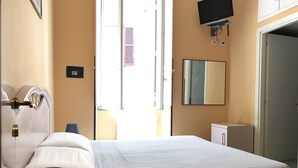 A hotel room with a bed, a bedside lamp, a TV mounted on the wall, and a door leading to another room. - San Daniele Bundi House (Rome)