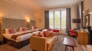 A hotel room with a large bed, two smaller beds, a sofa, a desk, and a TV. - City Apartments Glasgow (Glasgow)