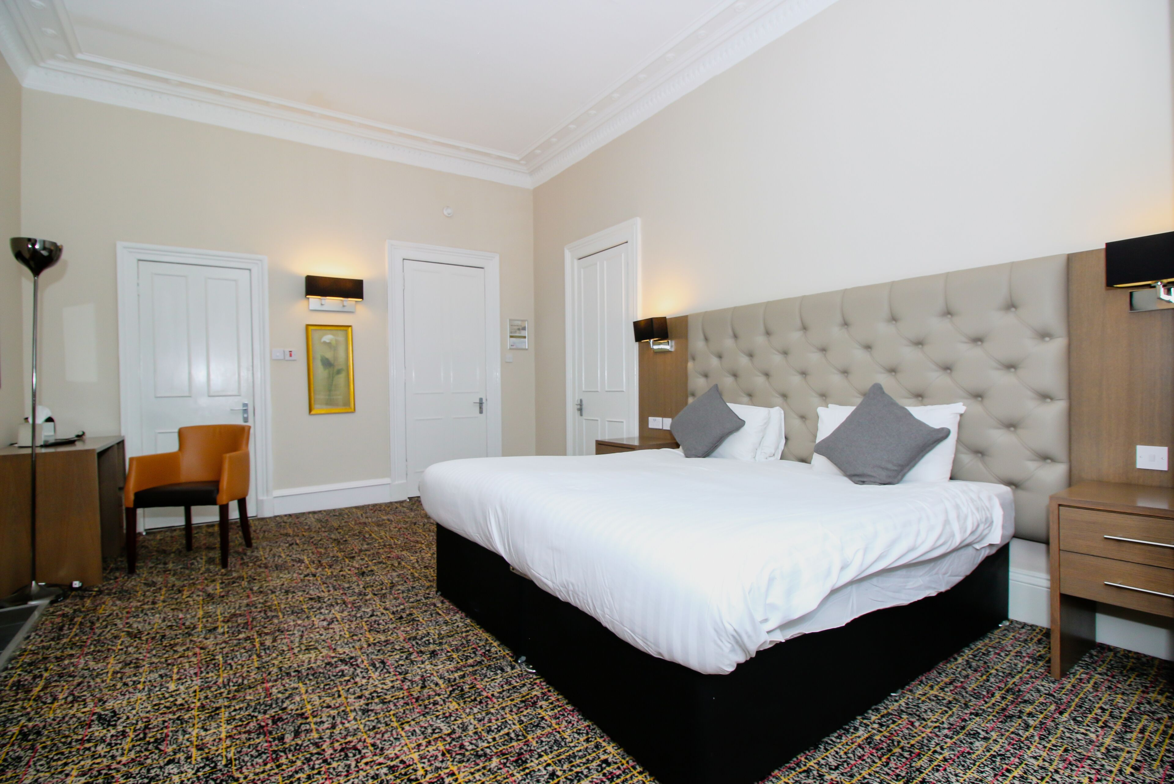 Een hotelkamer met een groot bed, een stoel, een bureau en een wandlamp.