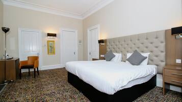Een hotelkamer met een groot bed, een stoel, een bureau en een wandlamp.