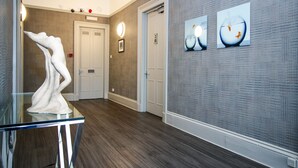 A hallway with a glass table, a white sculpture, and two fish-themed paintings on the wall. - City Apartments Glasgow (Glasgow)