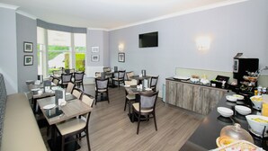 A modern dining area with multiple tables and chairs, a buffet station, and a flat-screen TV mounted on the wall. - City Apartments Glasgow (Glasgow)