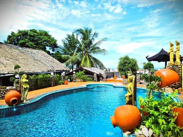 A swimming pool with a tropical setting, including palm trees and traditional architecture. - Boomerang Village Resort Kata (Karon)