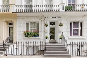 A white building with a balcony, a sign reading 'Falcon Hotel,' and a number '11' on the door. - Falcon Hotel (London)