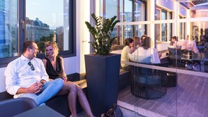 Un área de estar interior moderna con ventanas amplias, una planta en maceta central y una partición de vidrio.