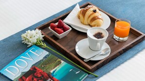 A breakfast tray with croissant, strawberries, a glass of orange juice, and a cup of coffee, alongside a magazine and a flower. - Fiorentini Residence (Naples)