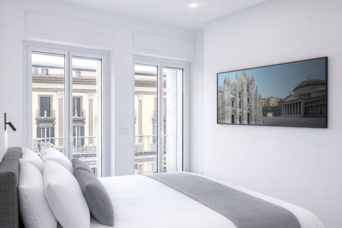 A modern bedroom with a large bed, a cityscape view, and a framed picture on the wall.