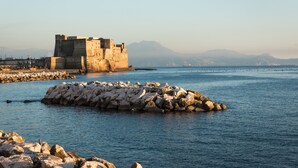 A coastal fortification with a large rock formation in the foreground and a clear view of the sea. - Fiorentini Residence (Naples)