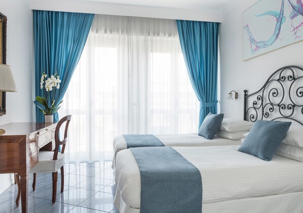 A hotel room with two beds, a desk, and a chair.