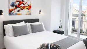 A modern bedroom with a large bed, a city view, and a painting on the wall. - Fiorentini Residence (Naples)