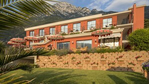 A hotel with a reception area, multiple balconies, and outdoor seating. - Hotel Oasi Beach (Malcesine)
