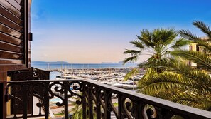 Un balcon donnant sur une marina et des palmiers.