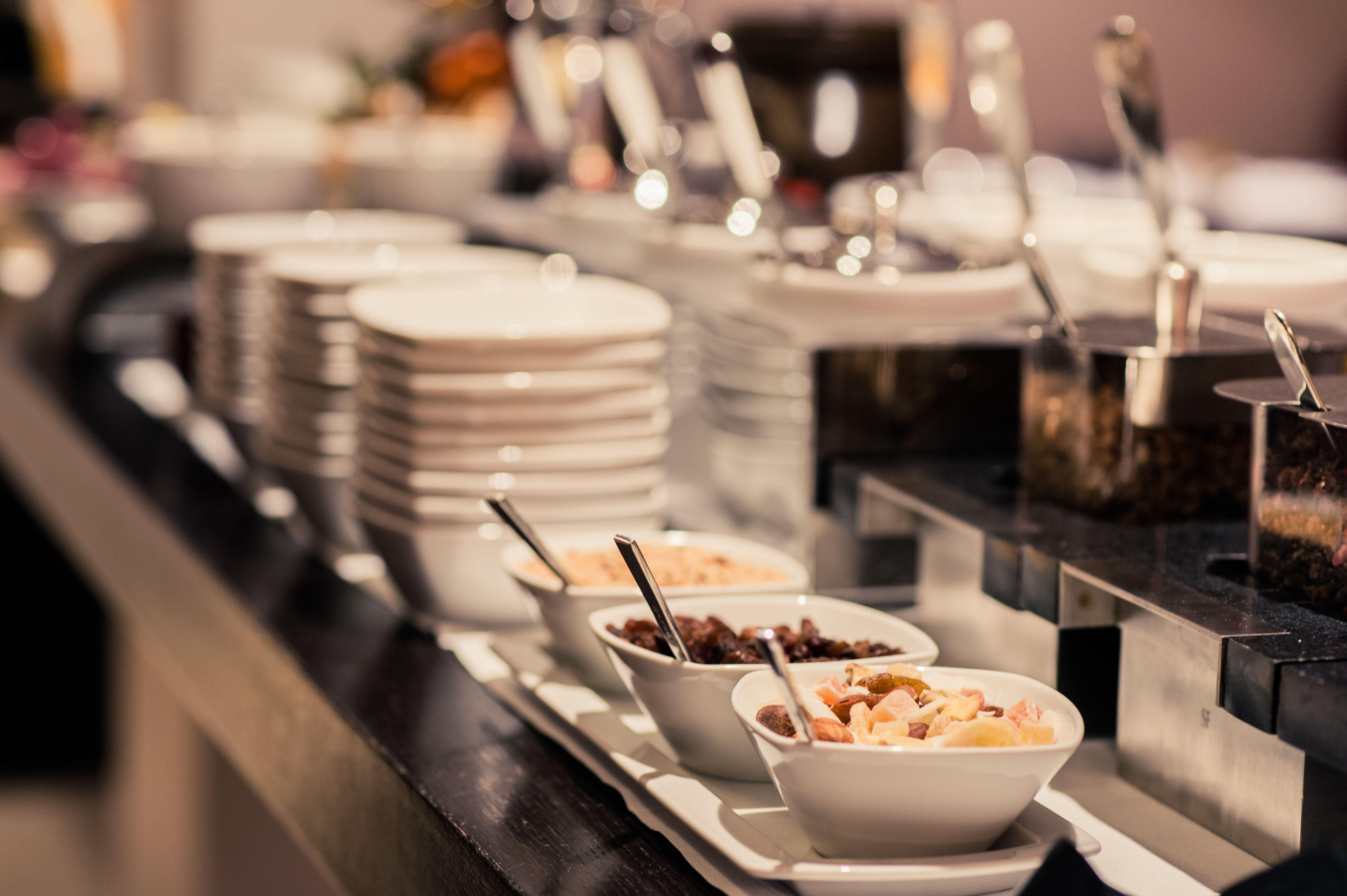 A buffet setup with multiple bowls of food and stacked plates.