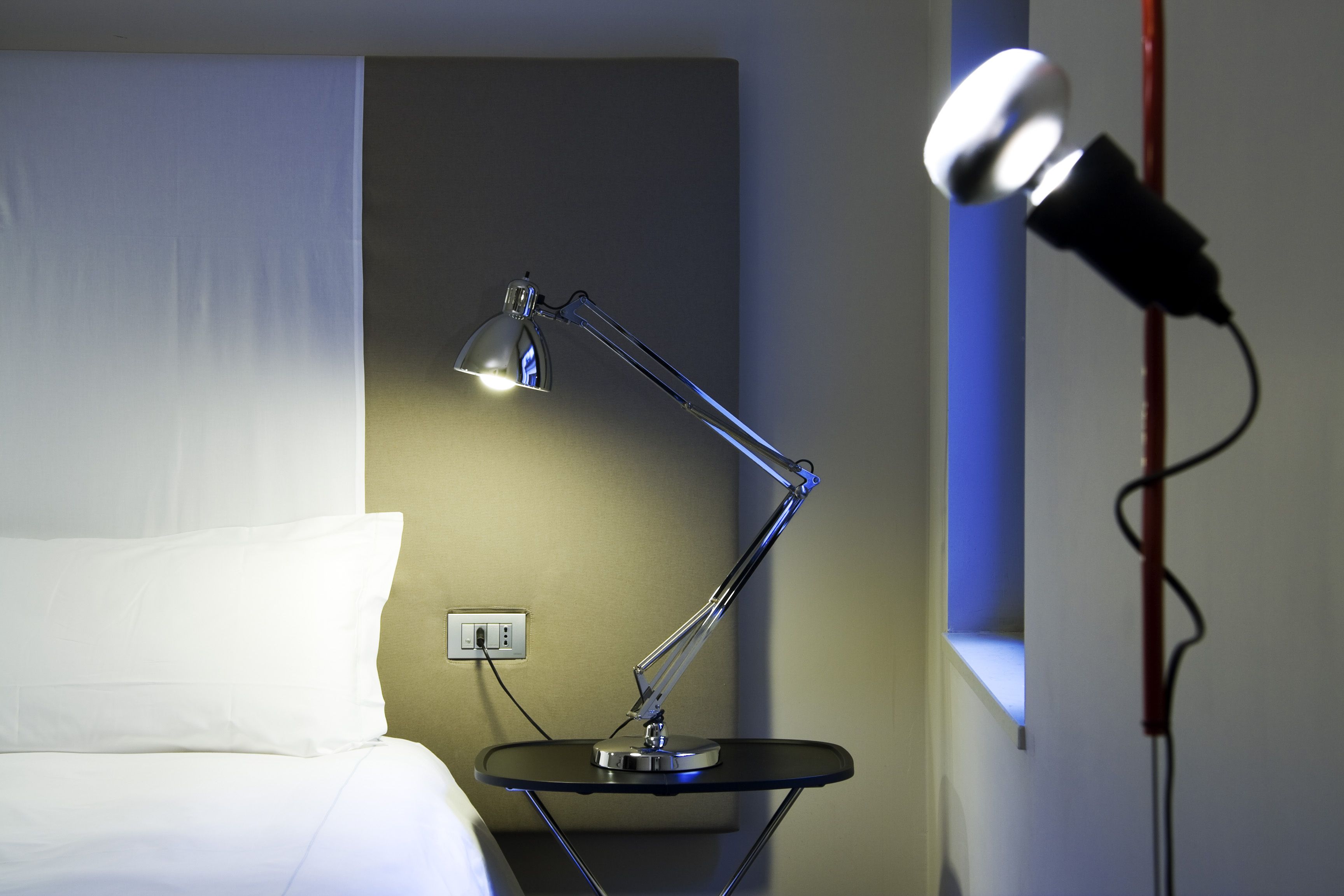 A modern room with a bed, a desk lamp, and a microphone.