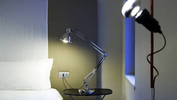 Una habitación moderna con una cama, una lámpara de escritorio y un micrófono.